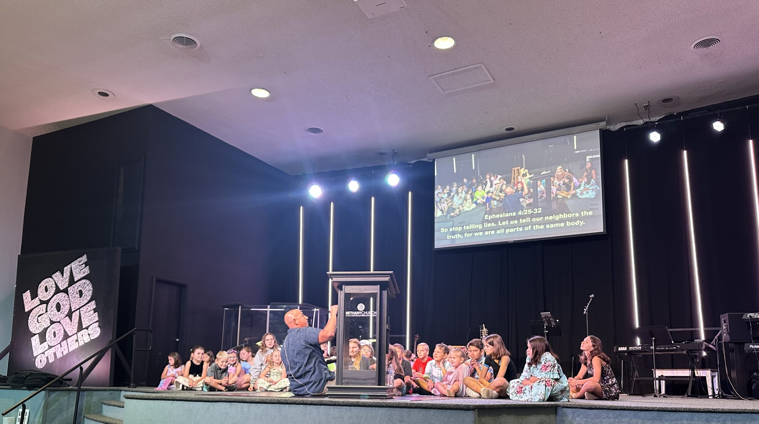 Pastor Andy speaking with children on stage during a Bethany Church service