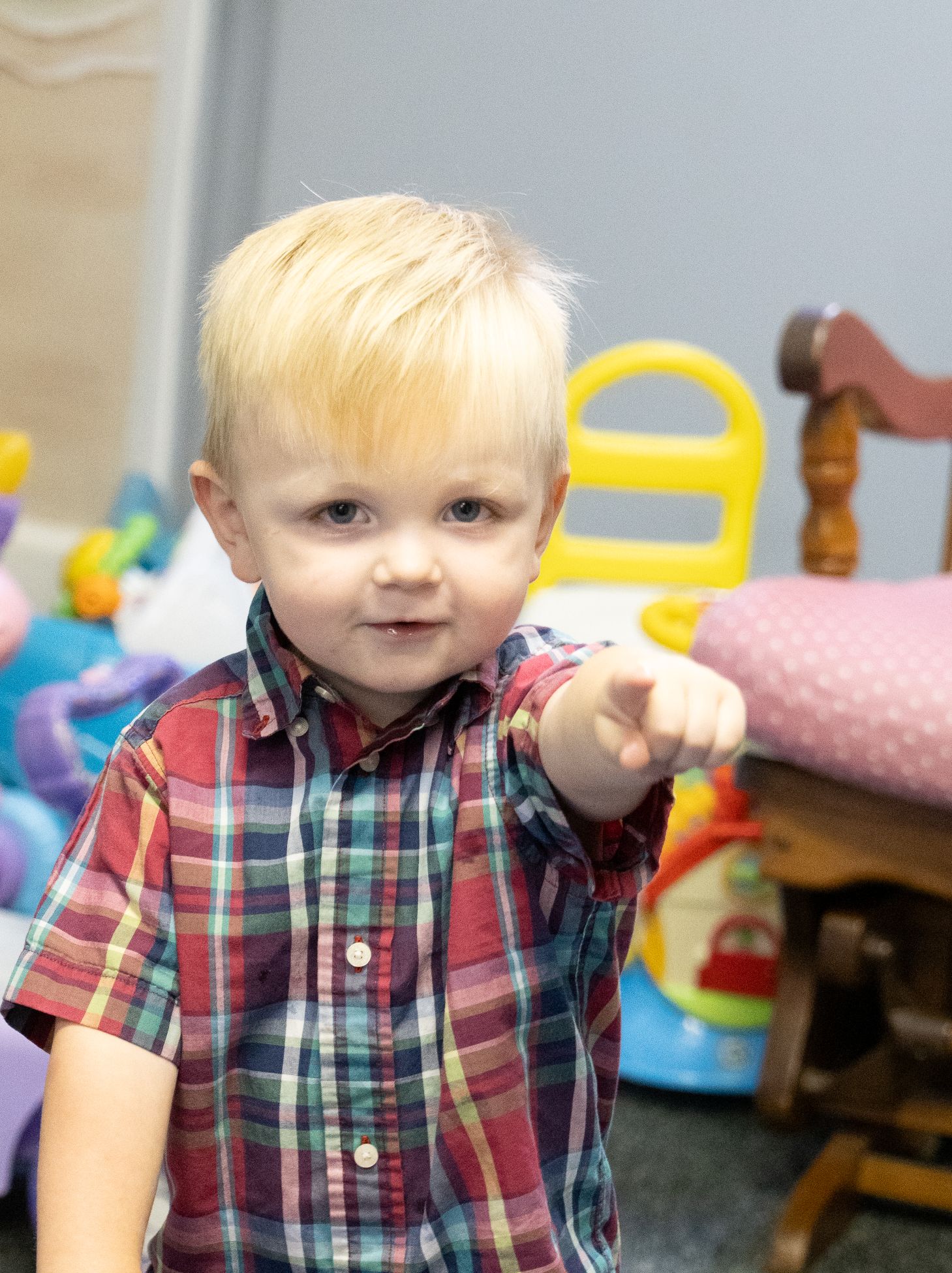 Toddler standing and pointing while playing in the Little Ones ministry area