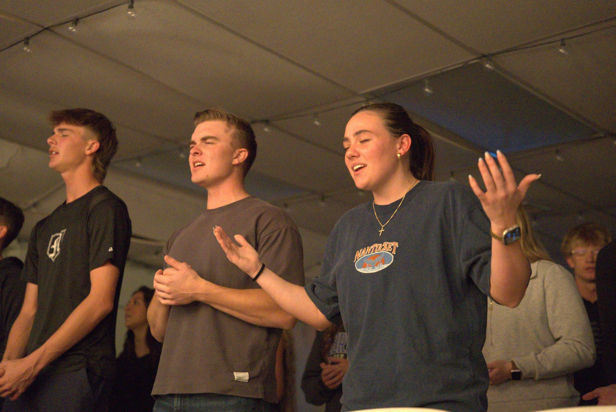 Young woman holding a microphone and smiling during The Pursuit young adults gathering