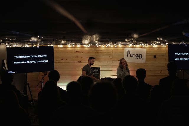 The Pursuit worship gathering with young adults standing together in the room